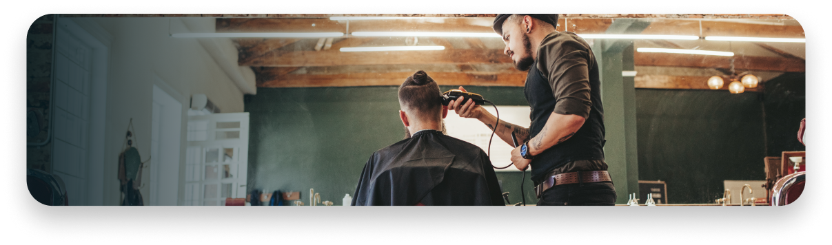 Un barbero le corta el pelo a un hombre en una barbería.
