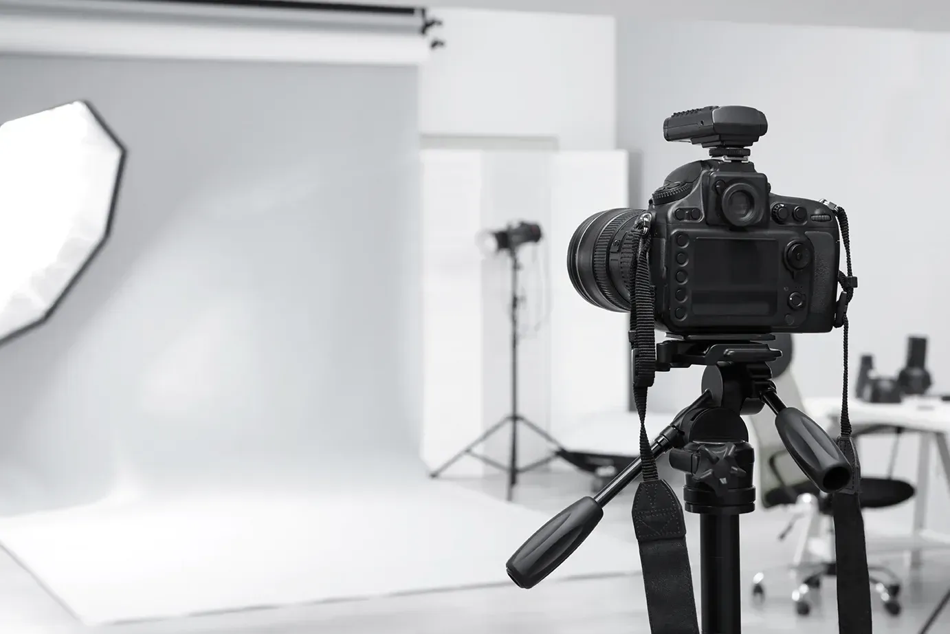 Cámara sobre trípode en un estudio de fotografía, con softbox y telón de fondo.