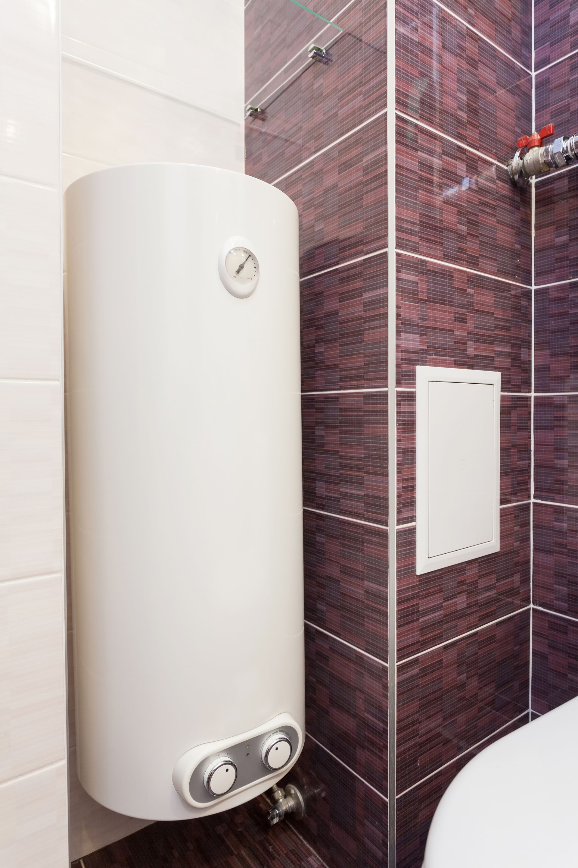 Chauffe-eau accroché au mur carrelé dans un renfoncement