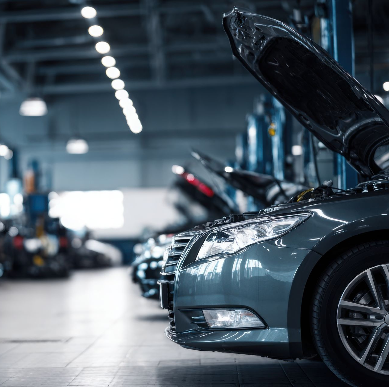 Un mécanicien en combinaison bleue examine le moteur d'une voiture à l'aide d'une lampe torche.