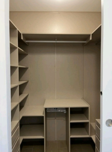 Vestidor con estanterías, cajones y barra para colgar. Colores neutros, líneas limpias y un espacio organizado.