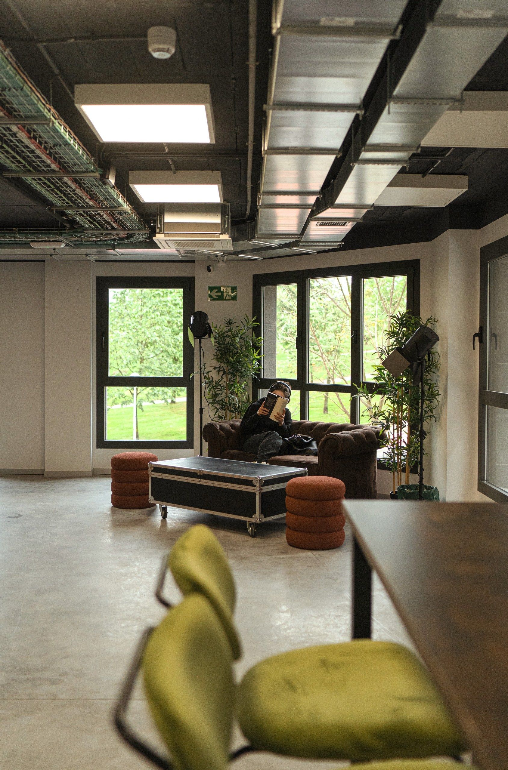 Un hombre está sentado en un sofá en una habitación con muchas ventanas.