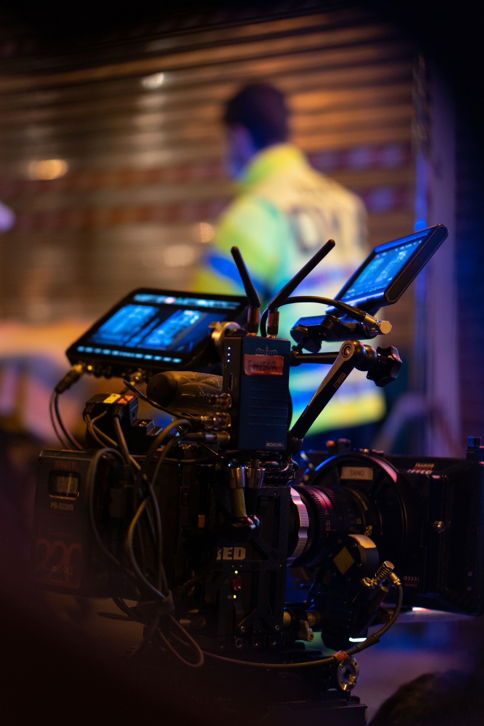 Un hombre está parado detrás de una cámara con dos monitores conectados a ella.