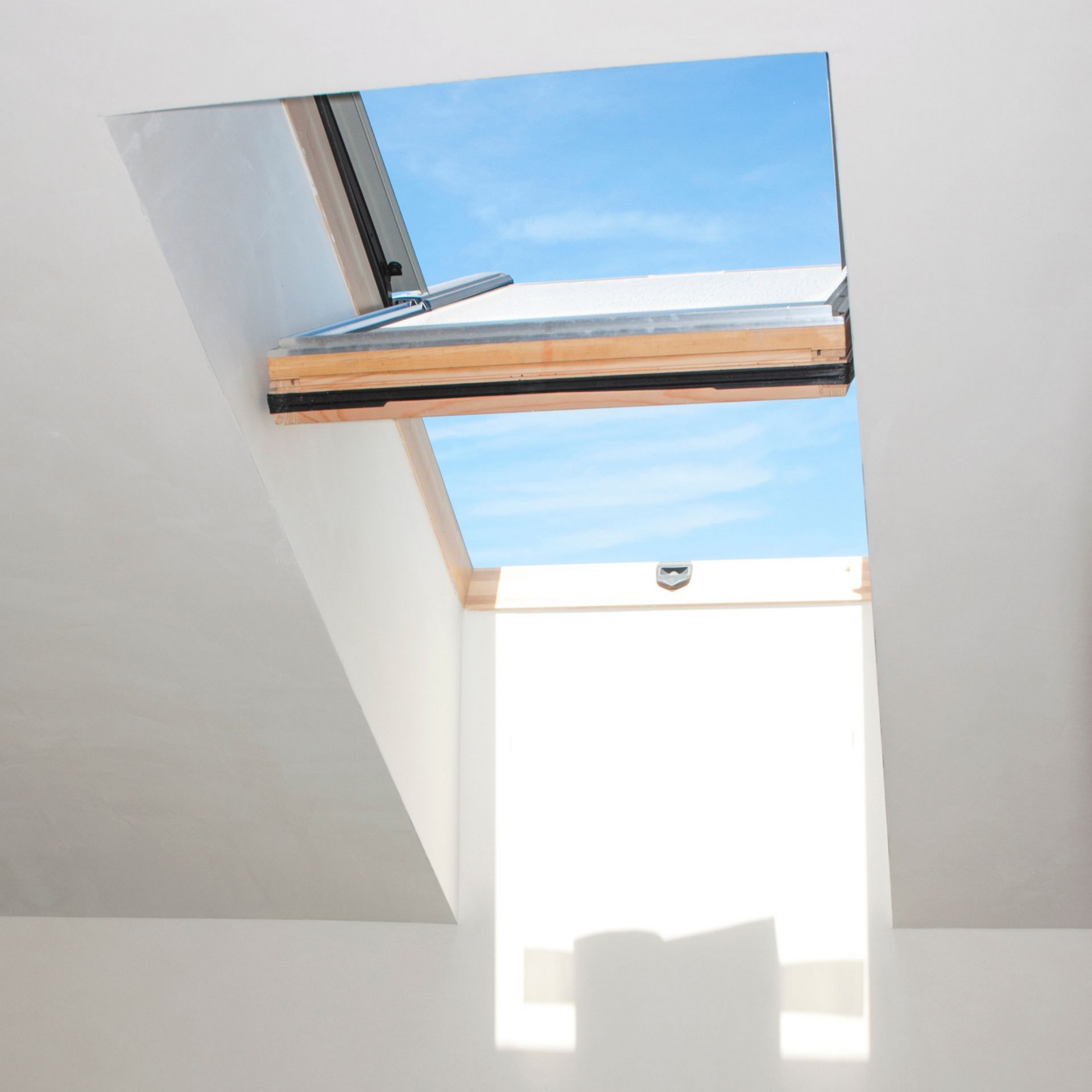 Puits de lumière dans un plafond blanc, ouvert sur le ciel bleu.