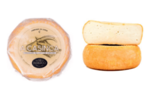 Une meule ronde et dorée de fromage de chèvre Casinca, présentée dans son emballage plastique à côté d'une tranche de meule.