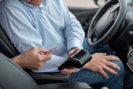 Un homme est assis dans une voiture en train de payer avec une carte de crédit.