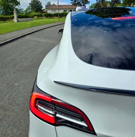 Une voiture blanche est garée sur le bord de la route.