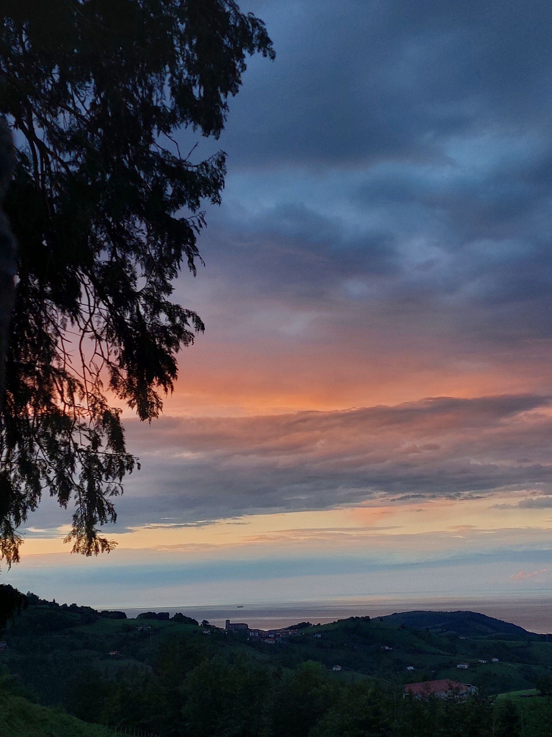 Casa blanca y de piedra bajo un cielo azul brillante con nubes blancas esponjosas.