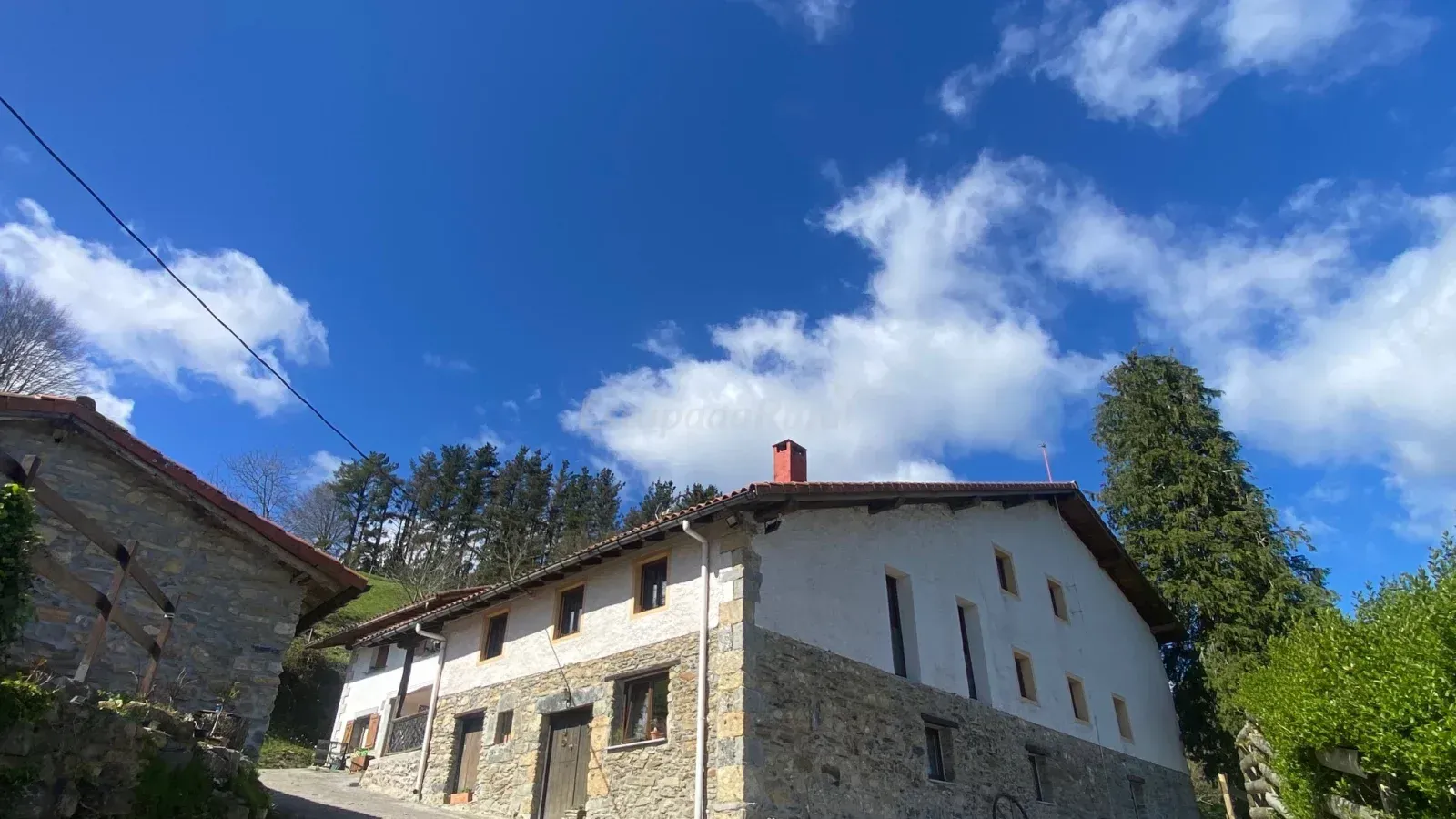 Una gran casa de piedra con techo rojo está situada en la cima de una colina.