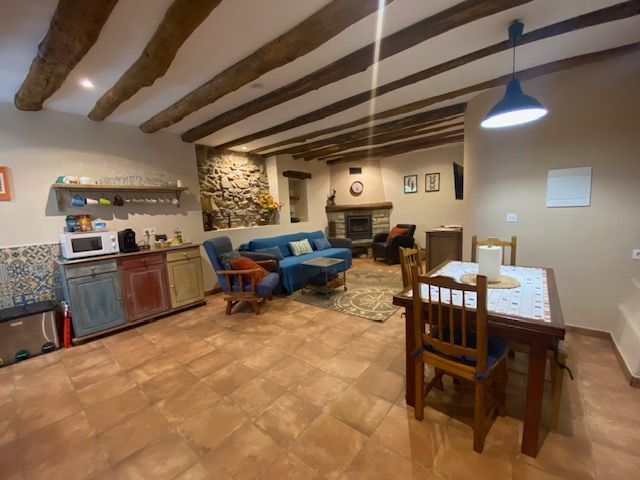 Acogedor espacio de estar con vigas de madera, chimenea de piedra y muebles rústicos.