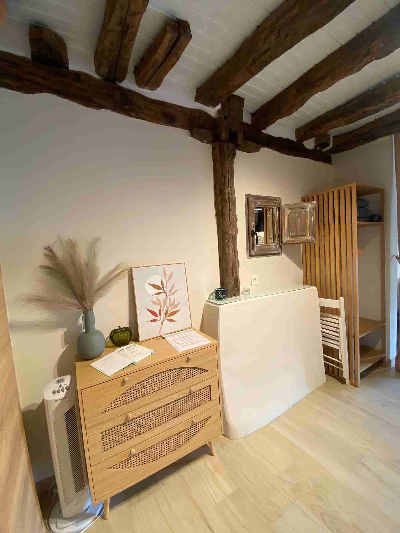 Cómoda de madera con arte y jarrón en habitación con vigas a la vista.