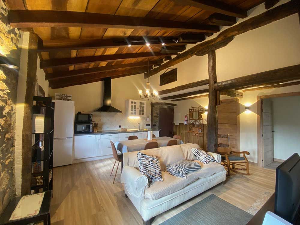 Una sala de estar con un sofá y una cocina al fondo.
