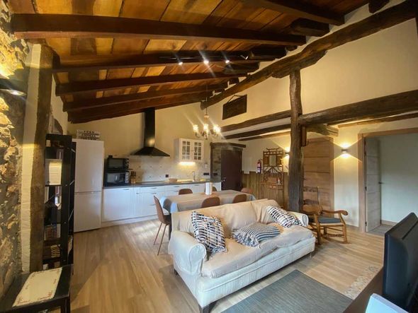 Una sala de estar con un sofá y una cocina al fondo.