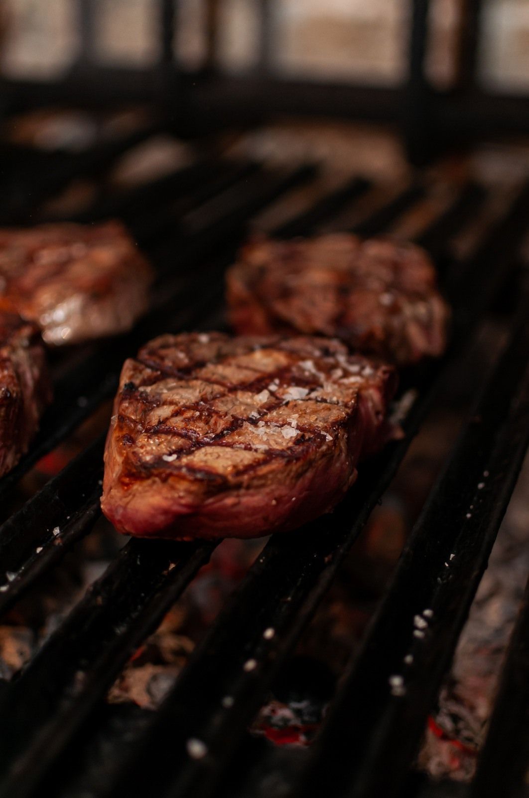 Filetes a la parrilla en una barbacoa caliente, con marcas de parrilla y espolvoreados con sal.