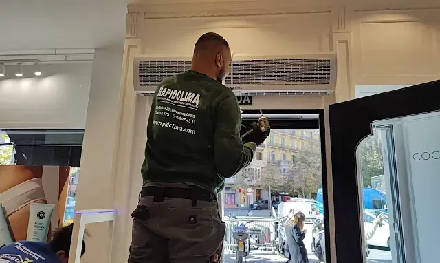 Un hombre con una camisa verde está trabajando en un escaparate de una tienda.