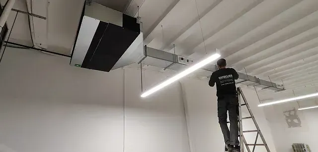 Un hombre está de pie en una escalera trabajando en un techo.