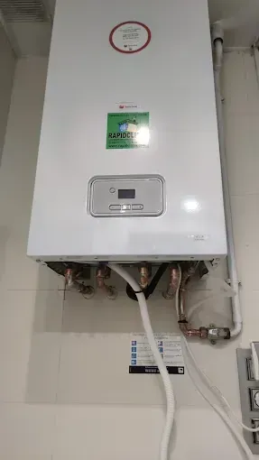 Una caldera blanca está colgada en una pared blanca.