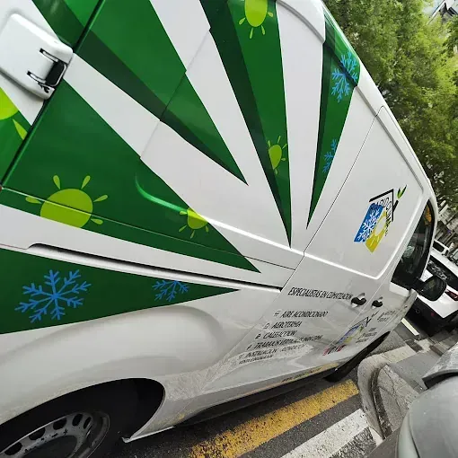 Una camioneta verde y blanca está estacionada al costado de la carretera.