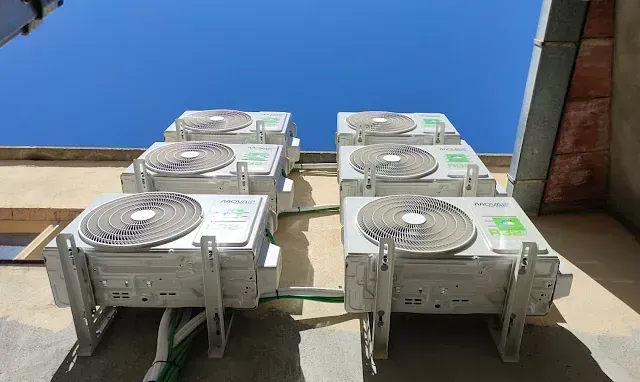 Una fila de aparatos de aire acondicionado están colocados al costado de un edificio.