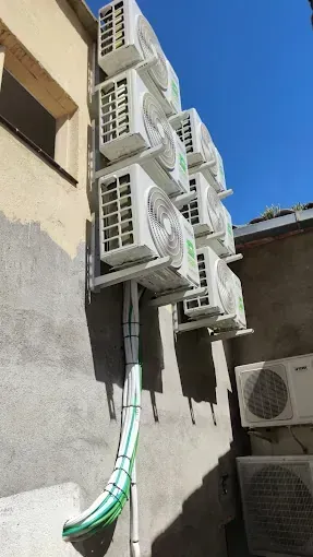 Una fila de aparatos de aire acondicionado están apilados uno encima del otro en el costado de un edificio.