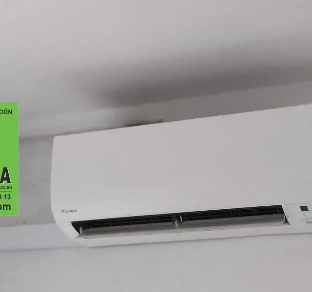 Un acondicionador de aire blanco cuelga del techo al lado de un cartel verde que dice a.