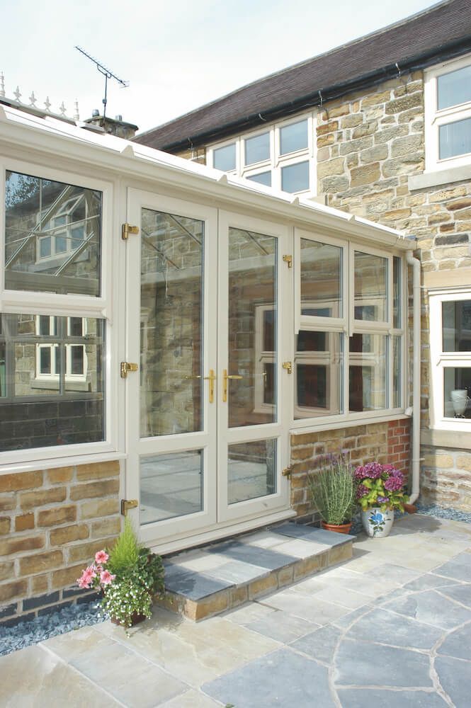 A house with a patio and a conservatory on the side of it.