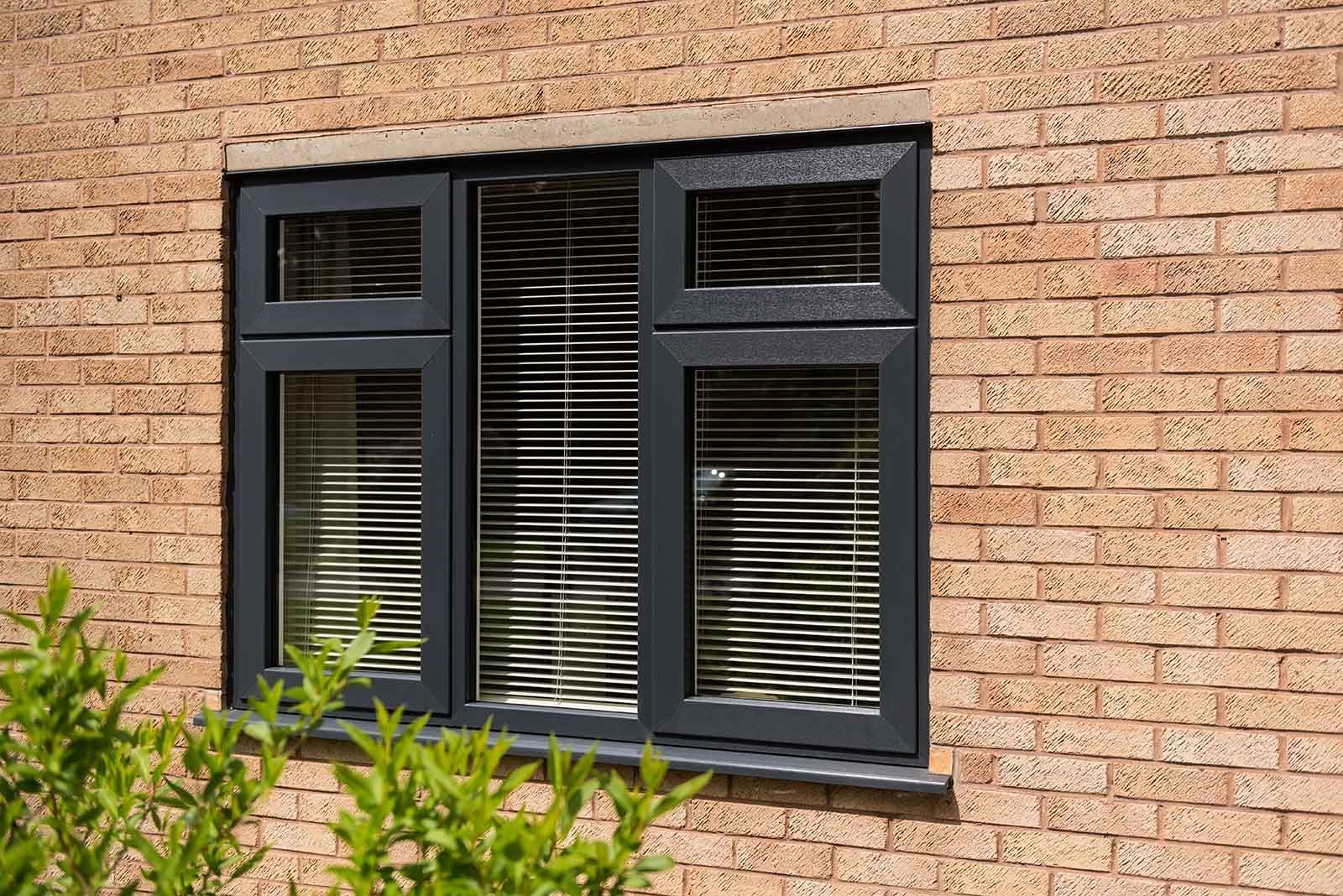 A black window with blinds on a brick wall.