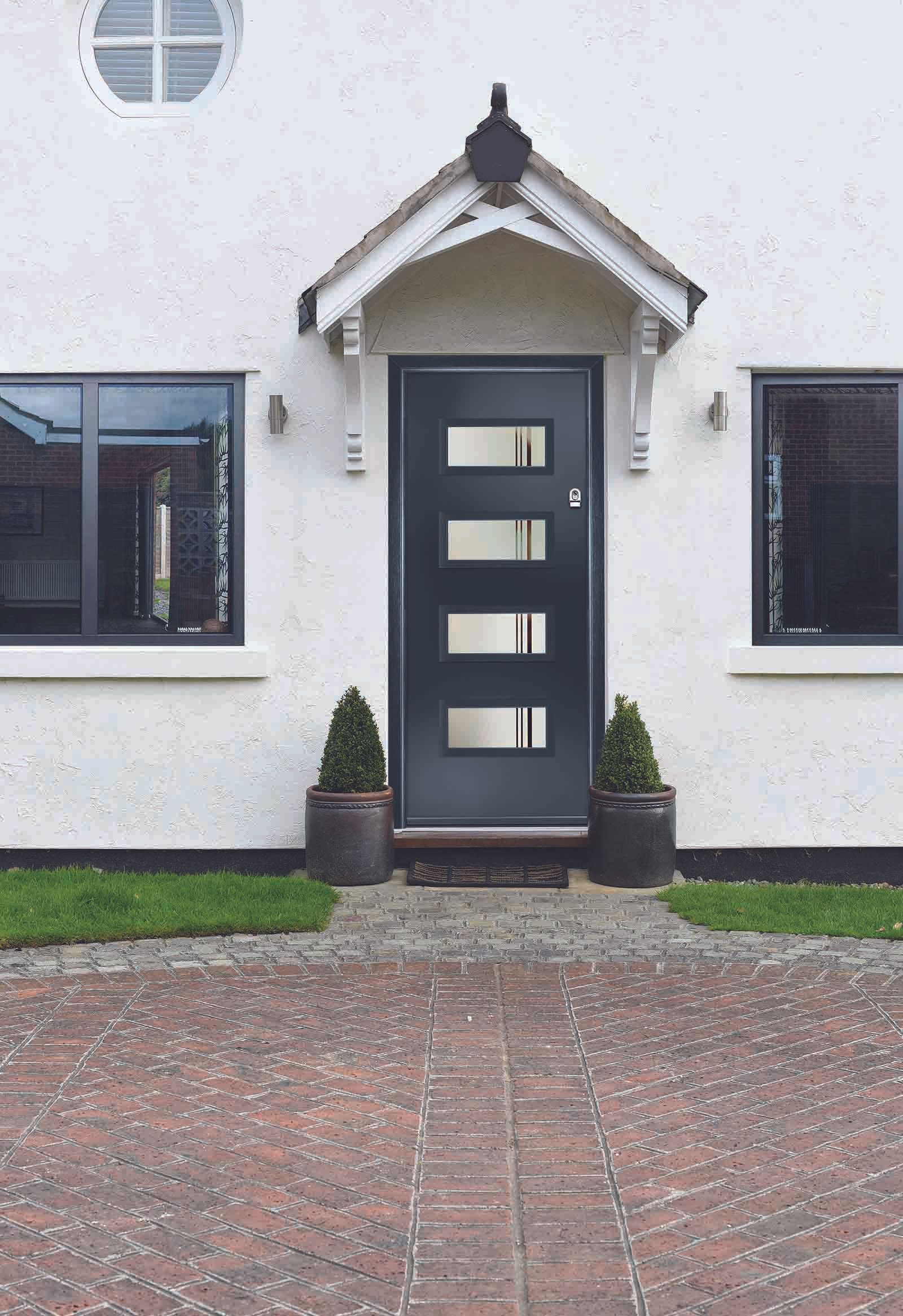 A white house with a black door and a brick driveway