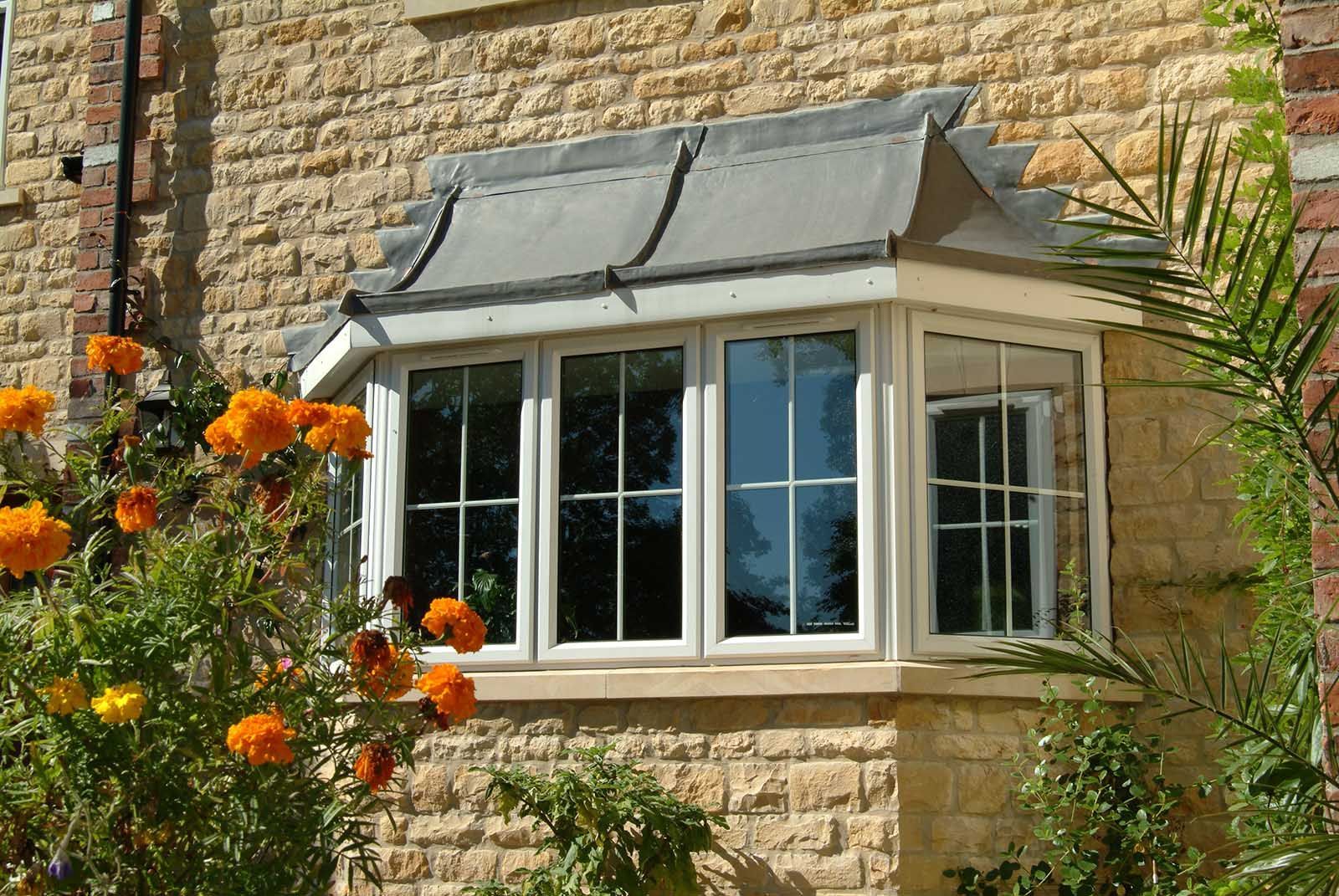 A large window on the side of a brick building with flowers in the foreground.