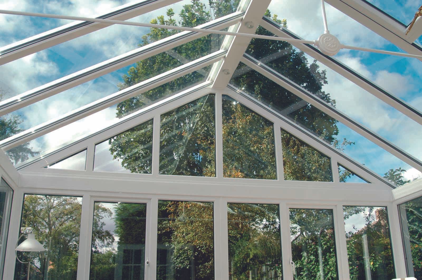 A conservatory with a glass roof and lots of windows