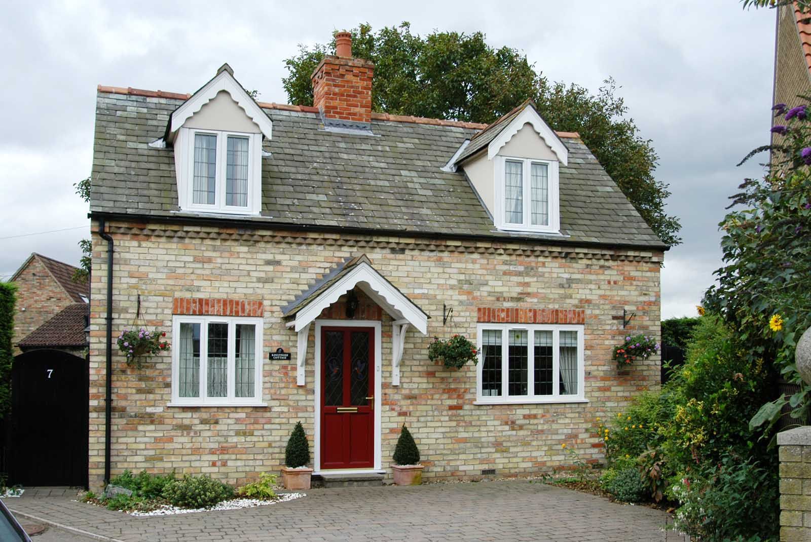 A brick house with a red door and white windows