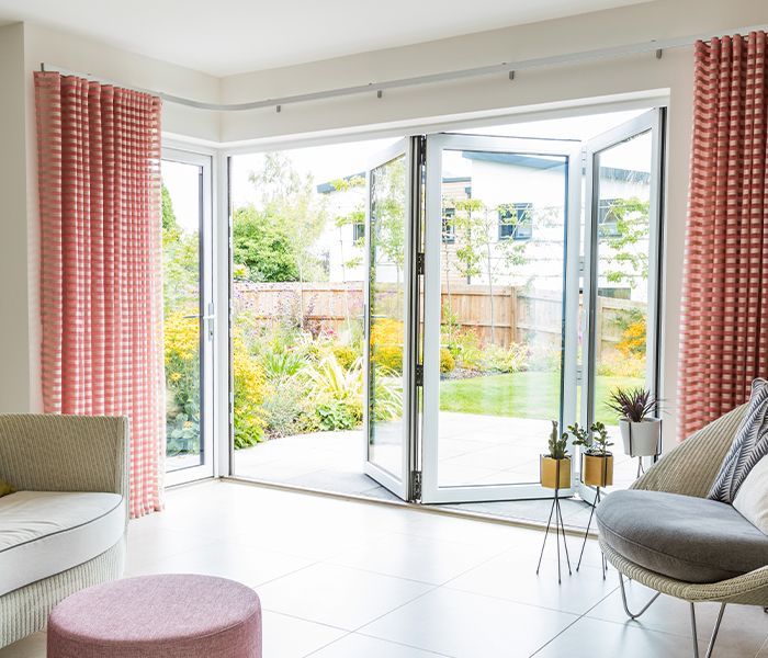 A living room with a couch , chair , ottoman and sliding glass doors.