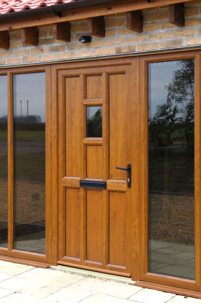 A wooden door with sliding glass doors on a brick building.