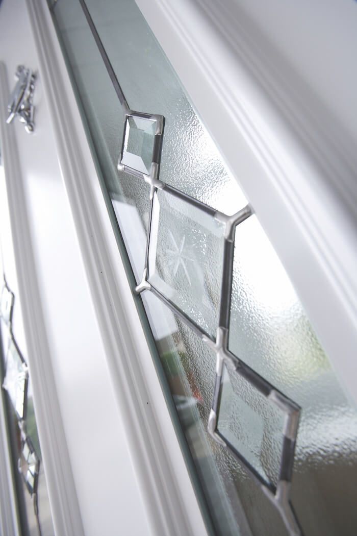 A close up of a stained glass window on a white door.