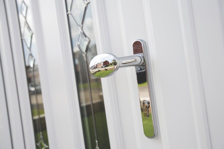 A close up of a door handle on a white door.