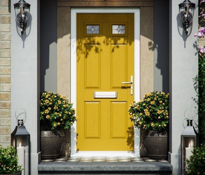 A yellow door with potted plants in front of it