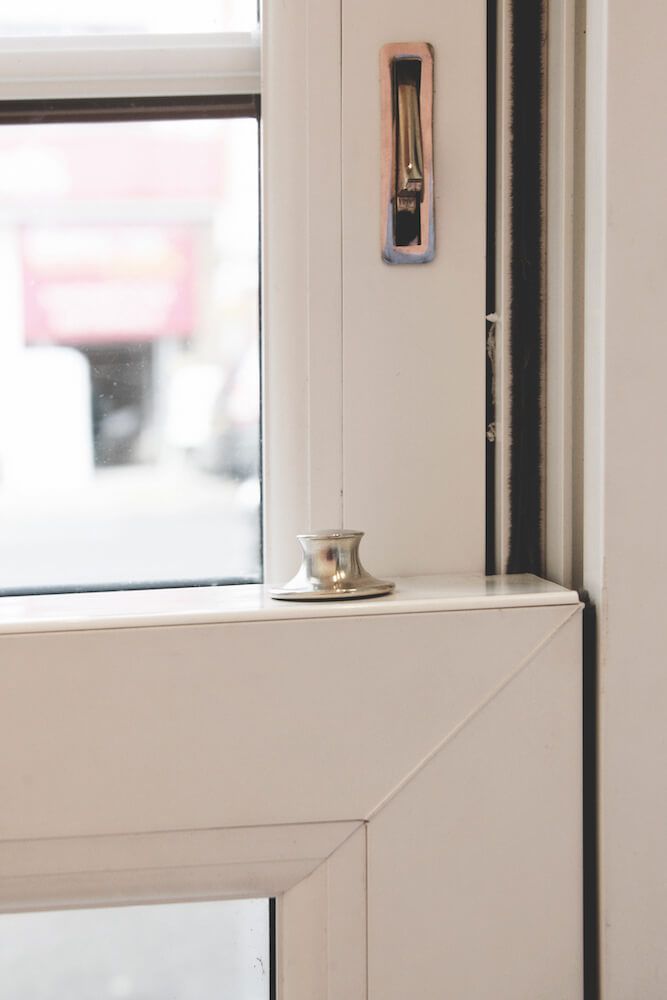 A candle holder is sitting on a window sill next to a window.