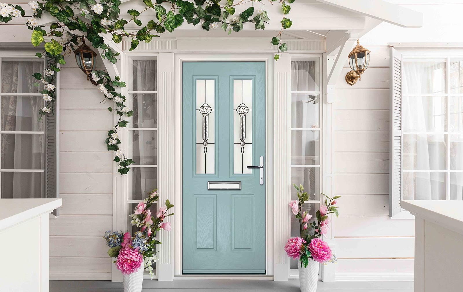 A white house with a blue door and flowers in front of it.