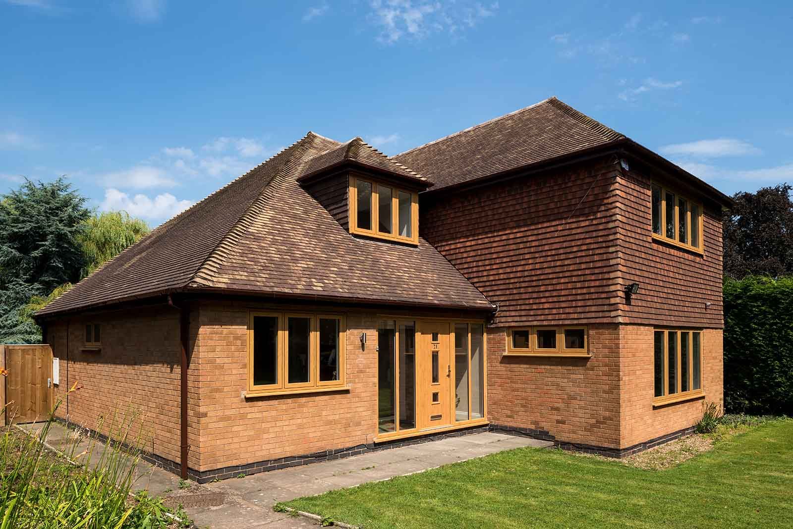 A large brick house with a brown roof and a lot of windows