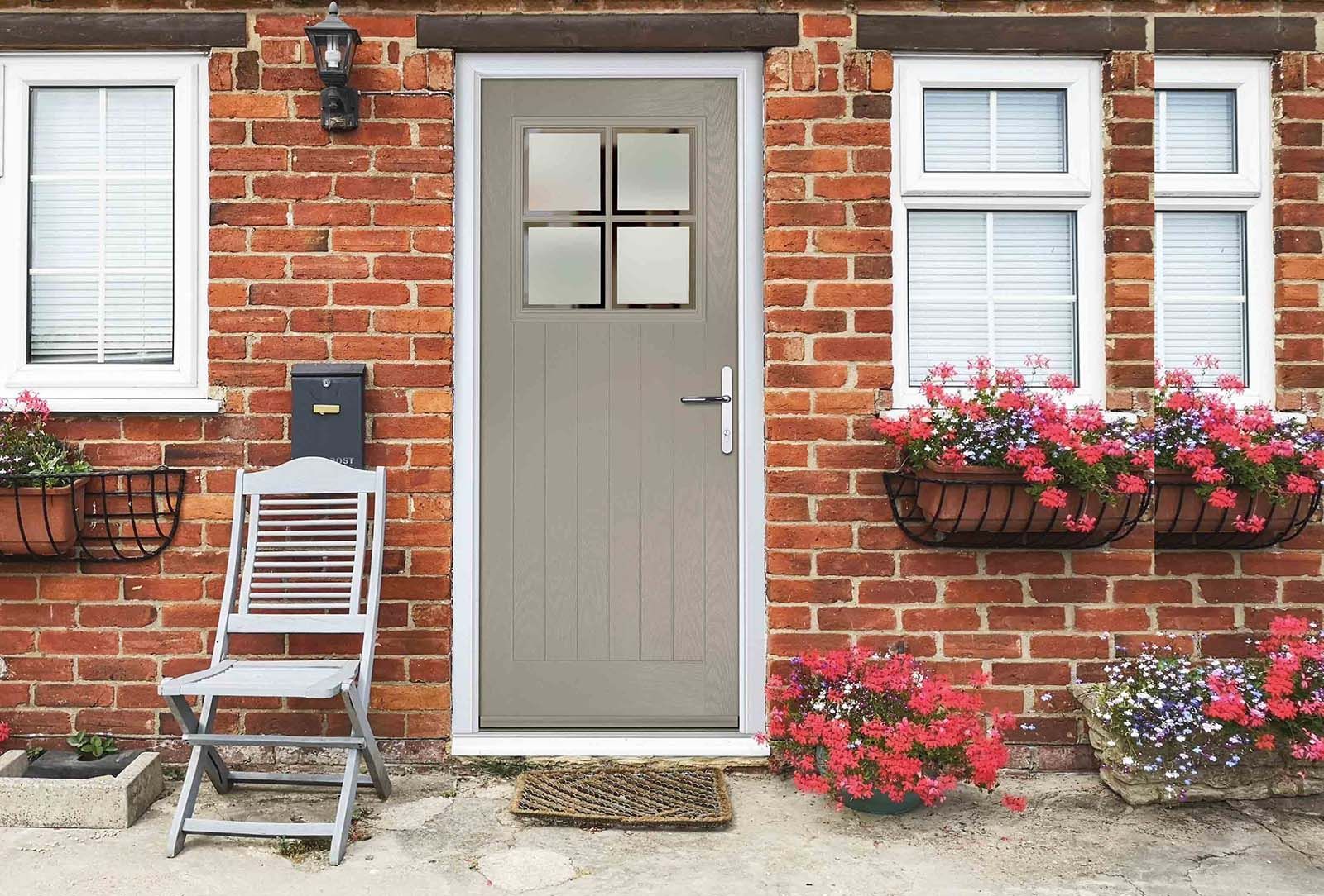 A brick house with a gray door and a chair in front of it.