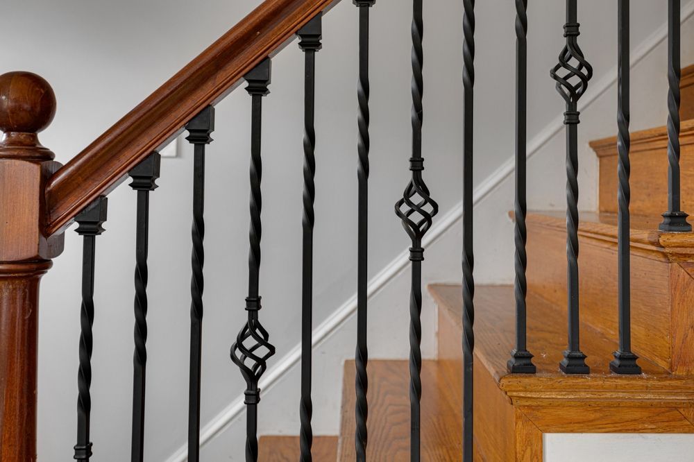 Escalera de madera con husillos de metal negro y pasamanos de madera oscura.