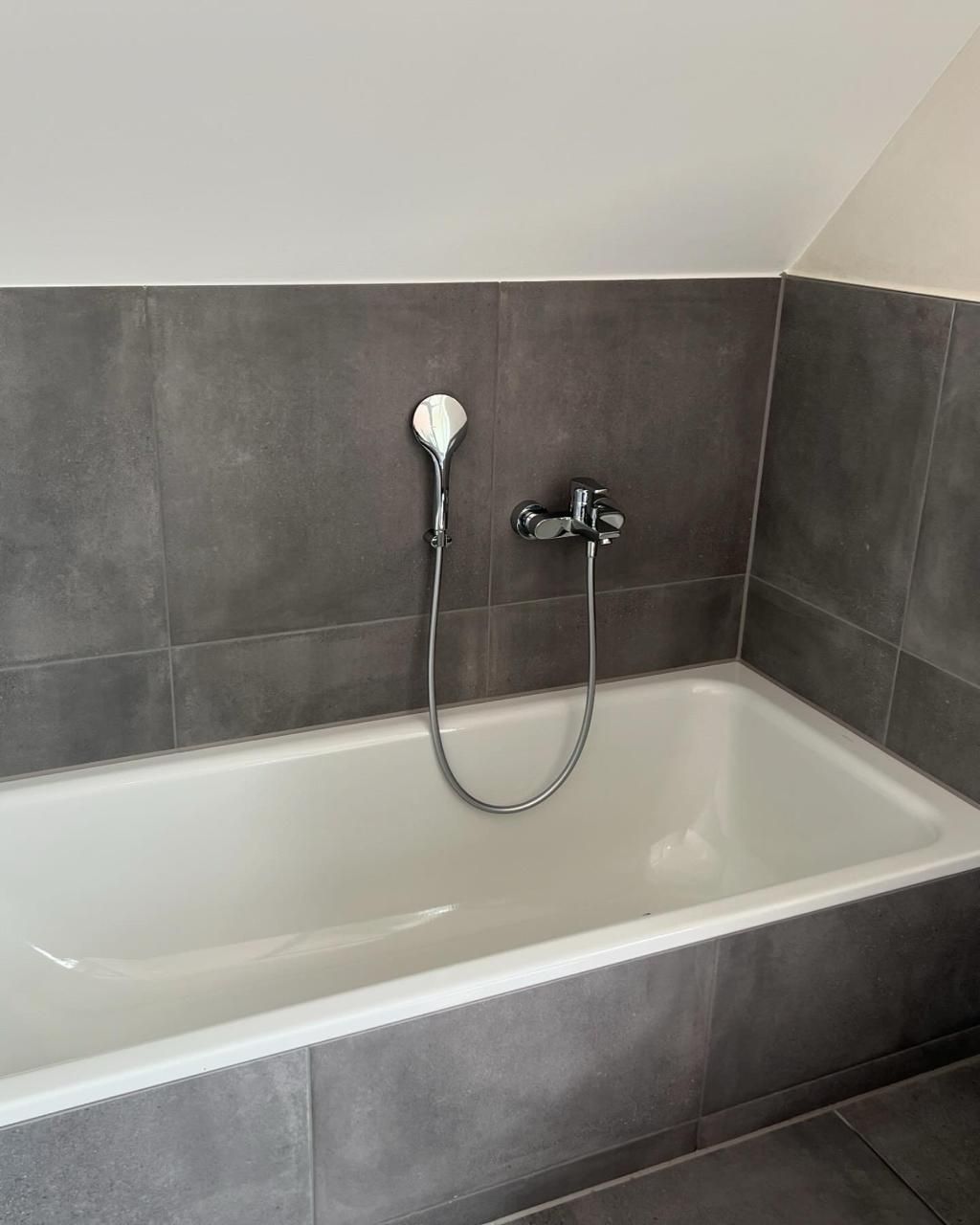 Eine Badewanne mit angeschlossenem Duschkopf in einem Badezimmer.