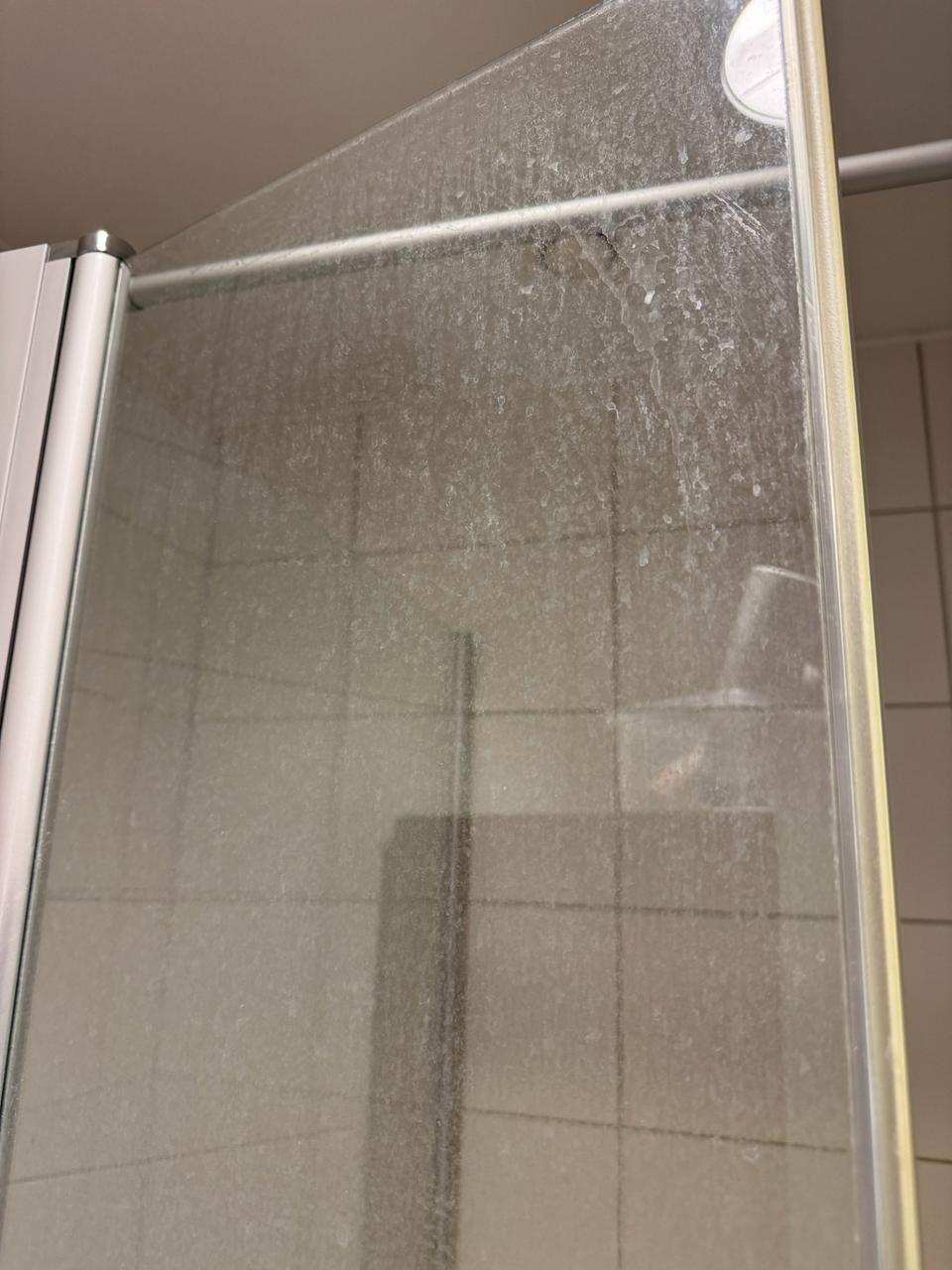 Eine Nahaufnahme einer schmutzigen Duschtür in einem Badezimmer.