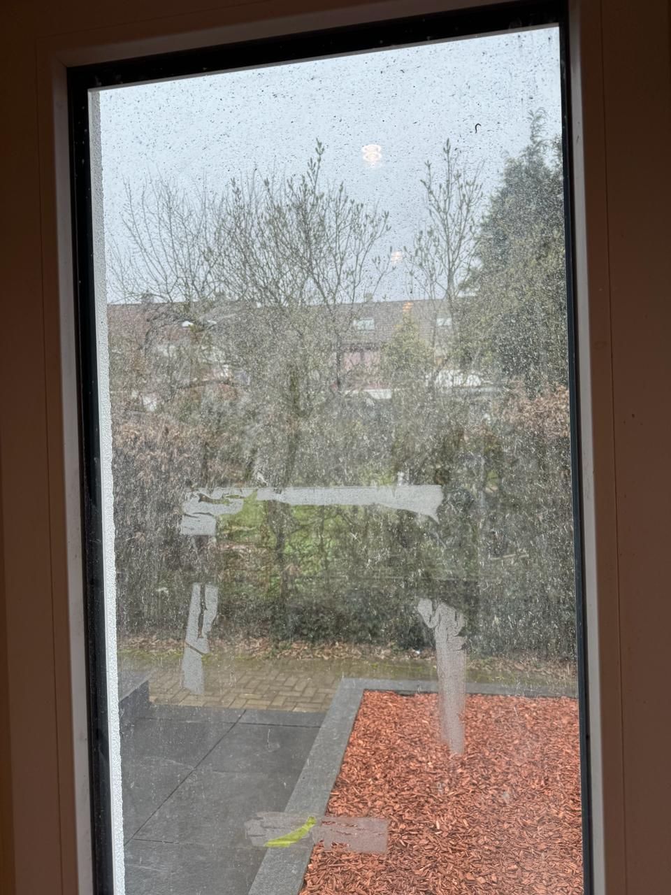 Ein Fenster mit Blick auf einen Garten und Bäume.