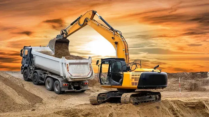 Una excavadora está cargando tierra en un camión volquete en un sitio de construcción.