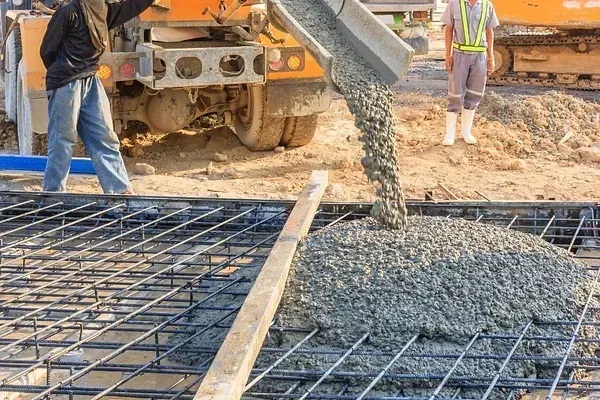 Un hombre está vertiendo hormigón en una losa de hormigón en un sitio de construcción.