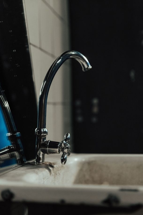 Robinet chromé au-dessus d'un lavabo de salle de bain avec un fond de miroir sombre