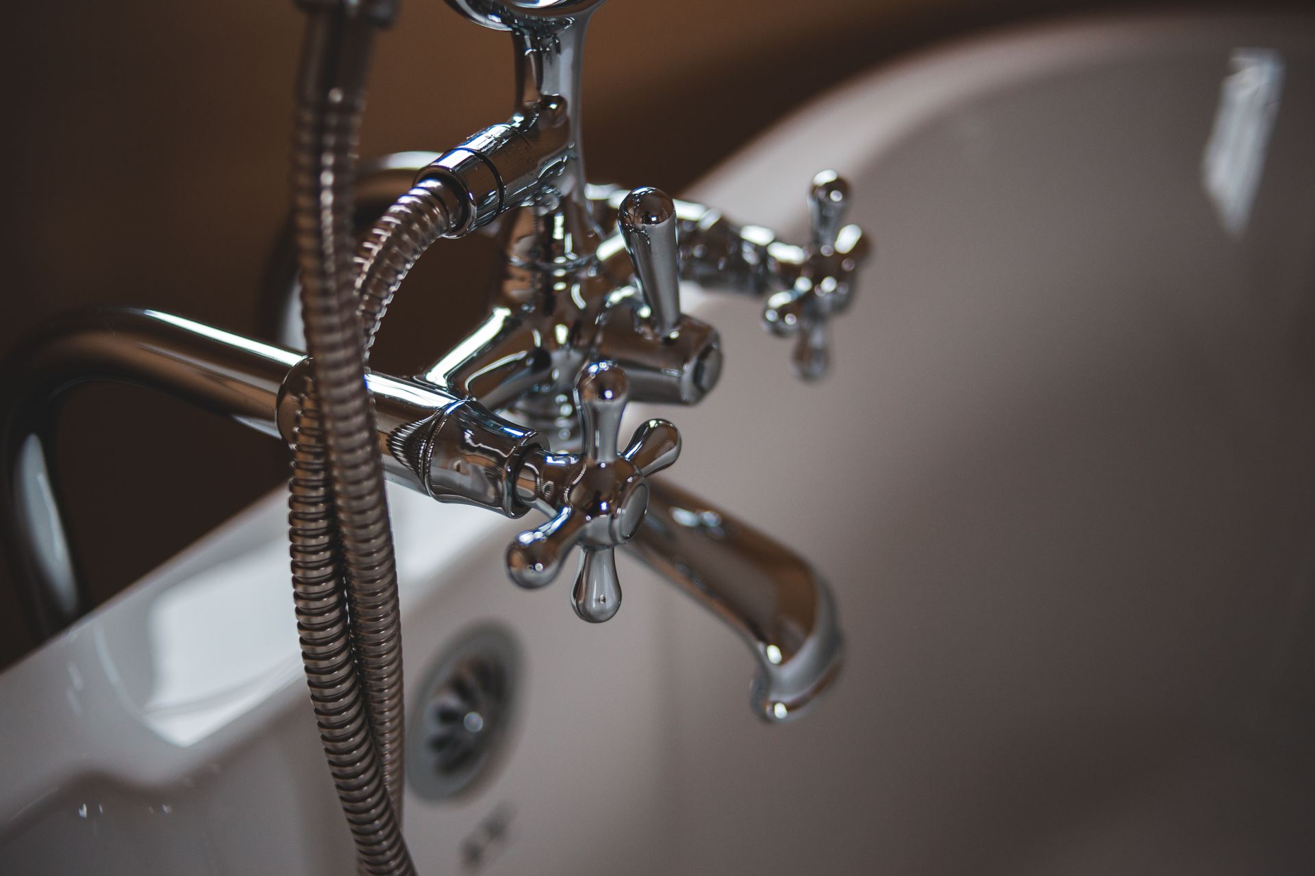 Robinet de salle de bains chromé au-dessus d'un lavabo blanc, l'eau s'écoulant dans le bassin.