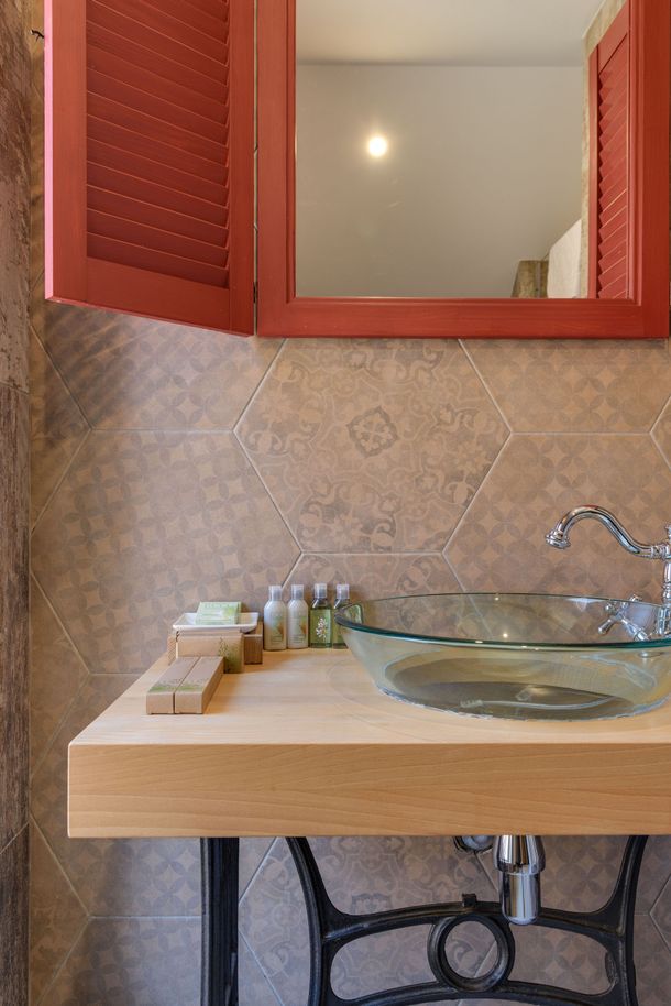 Meuble-lavabo de salle de bains avec comptoir en bois, lavabo en verre et armoire à miroir rouge au-dessus d'un mur carrelé.