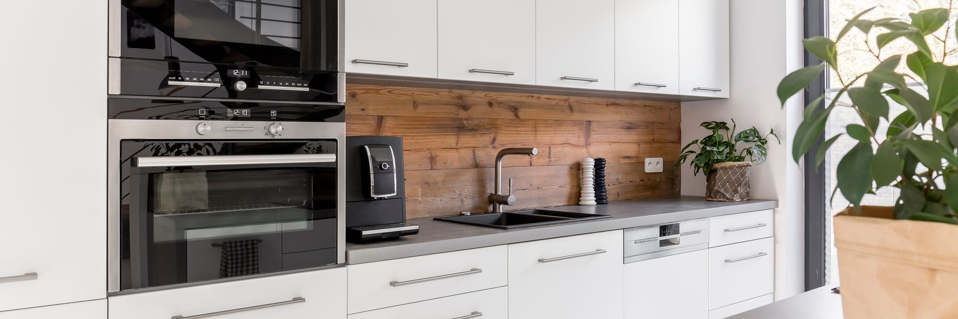 Une cuisine blanche avec une crédence en bois foncé